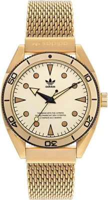 A close-up studio shot of a gold Adidas watch with a cream dial and a mesh band.