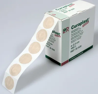 A roll of round, beige wound dressings is shown partially unrolled, with the product box in the background.