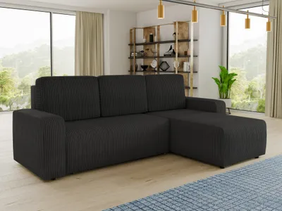 A dark grey sectional sofa is shown in a well-lit living room with large windows and a bookshelf in the background.