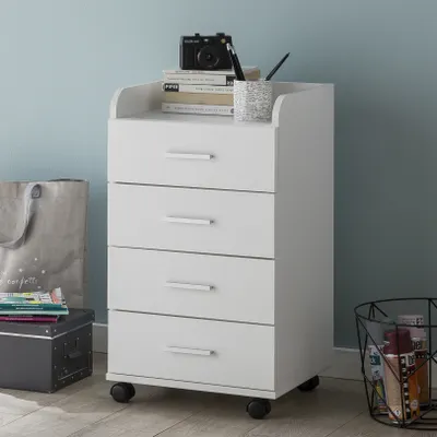 A white four-drawer rolling cabinet is shown in a room with a light blue wall and wooden floor. There are books, a camera, and a pen holder on top of the cabinet. A tote bag and a storage box are to the left, and a wire basket with items is to the right.