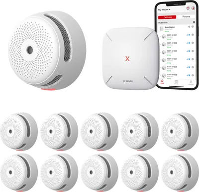 A collection of smart smoke detectors and a base station, along with a smartphone displaying the product's app interface.