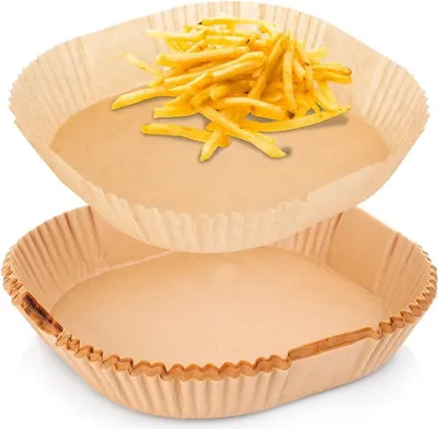 Two square paper liners for an air fryer, one with french fries on top.