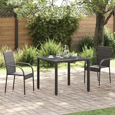 A patio set with two chairs and a table on a brick-paved patio, surrounded by greenery.