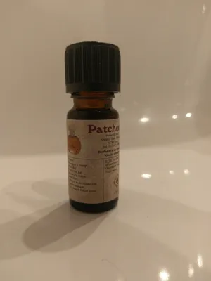 Kleine braune Flasche mit einem schwarzen Verschluss. Auf dem Etikett steht "Patchouli".