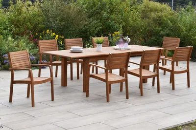 A wooden garden dining set with a table and chairs on a patio, surrounded by greenery.