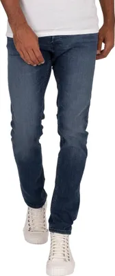 A person wearing jeans and sneakers, shown from the waist down.