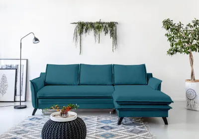 A teal sectional sofa is shown in a well-lit room with a white wall.