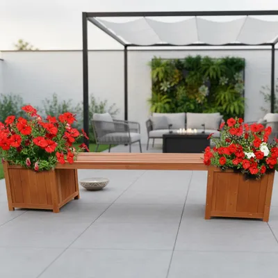 An outdoor patio scene with a wooden bench featuring integrated planters filled with red flowers, a pergola, and seating area in the background.