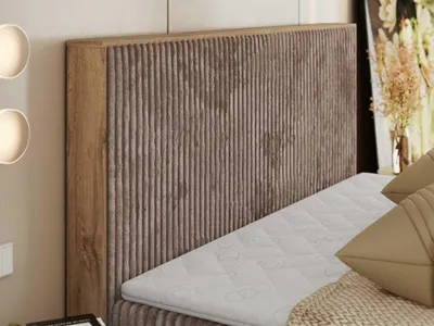 A close-up view of a bed with a textured headboard and mattress.