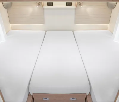 A view of a three-part bed setup in a recreational vehicle, with white bedding covering the mattresses.