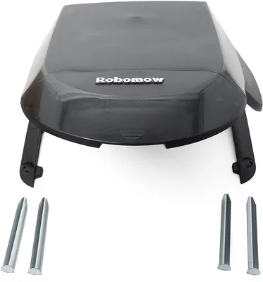 A dark gray robotic lawnmower garage with the brand name 'Robomow' visible on top, along with four metal stakes.