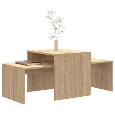 A set of nesting coffee tables with a book and a vase with a plant on them, presented on a white background.