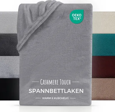 A folded gray blanket is shown with other colored blankets in the background, and a certification logo and text overlay.