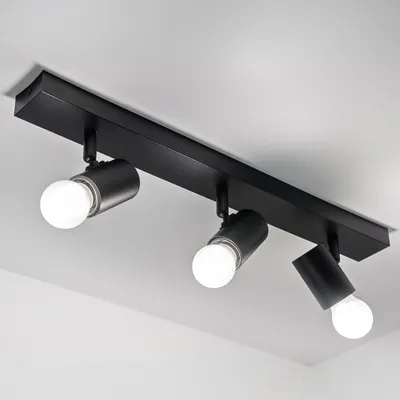 A black ceiling light fixture with three adjustable spotlights is mounted on a white ceiling.