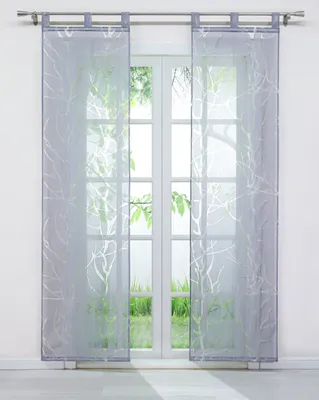 Two sheer gray curtains with a white branch pattern hang in front of a window.