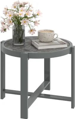 A round side table with a vase of flowers and a cup of coffee on it.