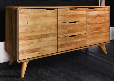 A wooden sideboard with drawers and doors, shown from the front in a room with a dark floor and black wall.