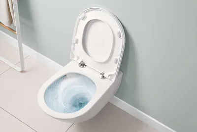 A wall-mounted toilet with the lid open and water swirling inside.