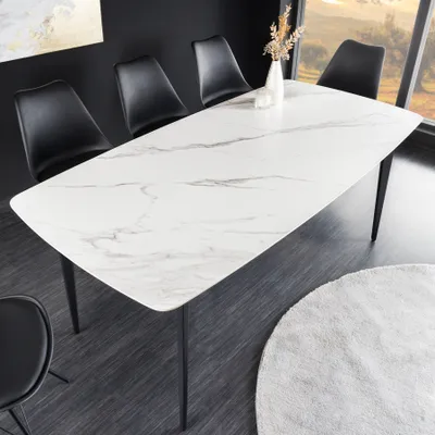 A modern dining room setting with a white marble-look table and black chairs.