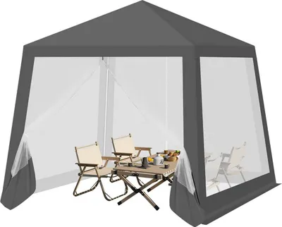 A gray gazebo with mosquito netting, set up with a table and chairs inside.