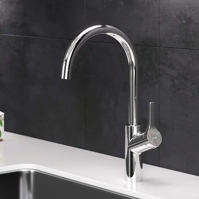 A modern kitchen faucet with a high arc and a single lever handle, installed on a white countertop with a dark tiled backsplash.