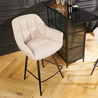 A bar stool is placed in front of a bar counter in a room with wooden flooring.