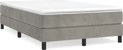 A studio shot of a boxspring bed frame with a white mattress topper and black legs, set against a white background.