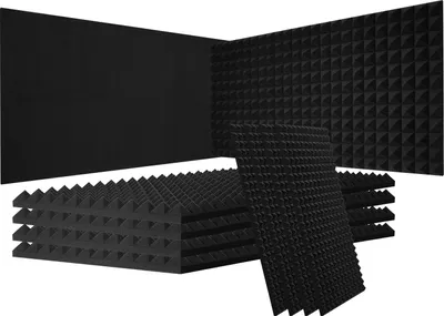 A collection of black acoustic foam panels with a pyramid texture, stacked and arranged in a corner.