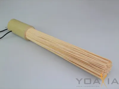 A bamboo wok brush on a plain gray background.