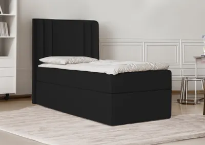 A black bed with a headboard is shown in a room with white walls and a light-colored rug.