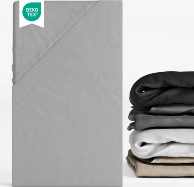 A folded grey fitted sheet is shown on the left, with a stack of fitted sheets in various colors on the right.