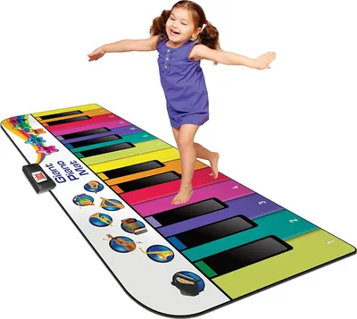 A young girl is happily playing on a giant piano mat.