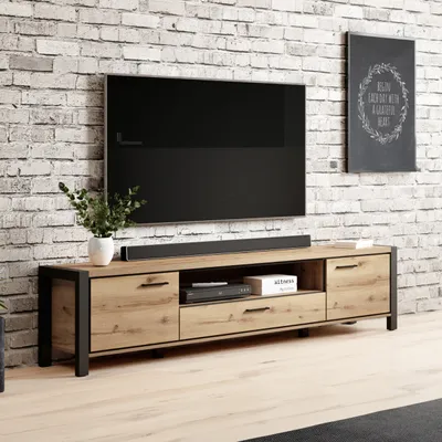 A TV stand with a TV and soundbar in a living room setting with a brick wall.
