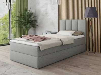 A bedroom scene with a bed, plant, and lamp.
