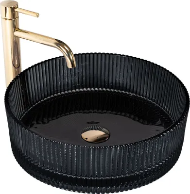 A black glass vessel sink with a gold faucet.