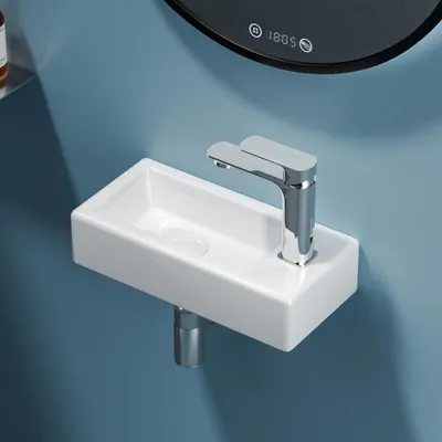 A close-up shot of a white rectangular sink with a chrome faucet mounted on a blue wall.