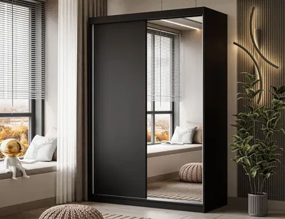 A modern bedroom with a large black sliding door wardrobe with a mirrored door, reflecting a window seat with cushions and a plant.
