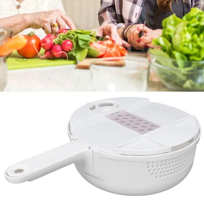 Two people are preparing vegetables in a kitchen, with a white vegetable slicer in the foreground.