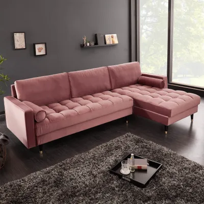 A pink velvet sectional sofa is shown in a modern living room setting with a dark gray wall and a large window.