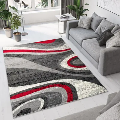 A modern living room with a gray sofa and a rug with a swirling pattern in red, gray, and cream.