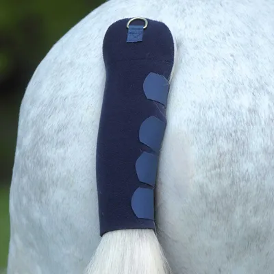 A close-up view of a horse's tail with a dark blue tail protector on it.