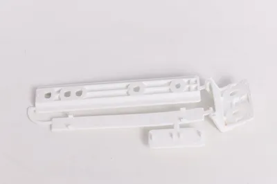 Several white plastic components, possibly a hardware kit for an appliance, are laid out on a white surface.
