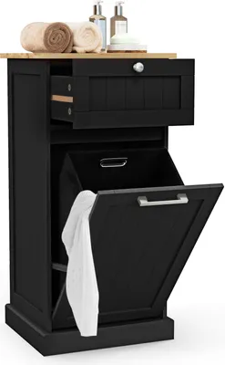 A black laundry cabinet with a drawer and a pull-down door revealing a laundry basket with a white towel inside. There are rolled towels and bottles on top.