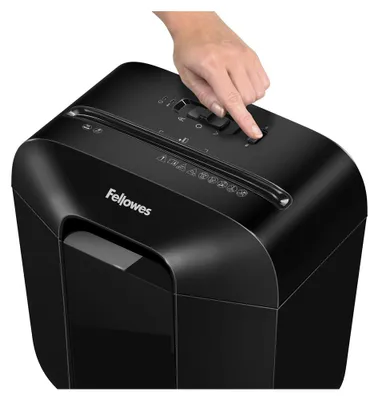 A hand is shown operating a black paper shredder.
