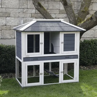 A multi-level wooden hutch for small animals, set up outdoors on a grassy lawn.
