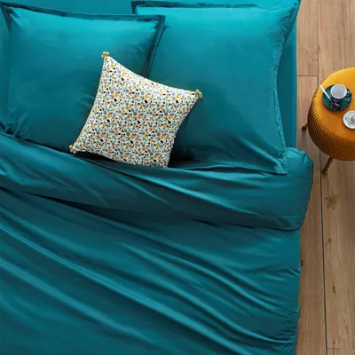 A close-up view of a teal duvet cover with a decorative pillow.