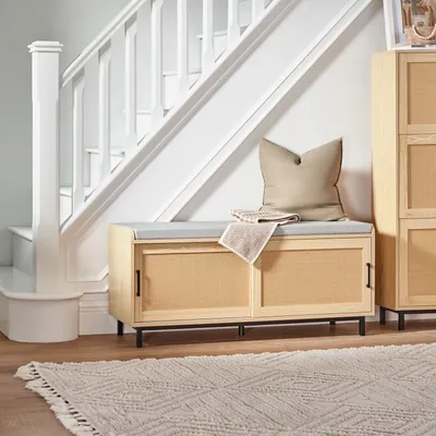 A hallway or entryway scene with a bench, stairs, and a cabinet.