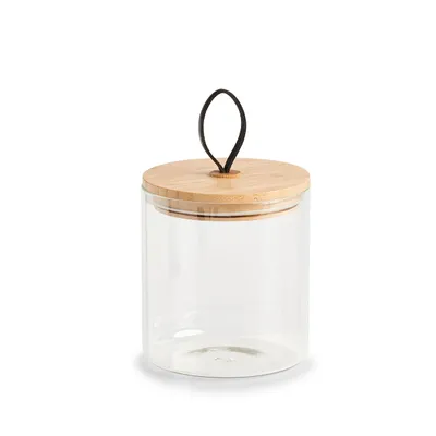 A clear studio shot of a glass storage jar with a bamboo lid and a black loop handle.