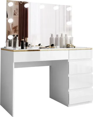 A white vanity table with a large mirror and lights, featuring makeup and skincare products on its surface.