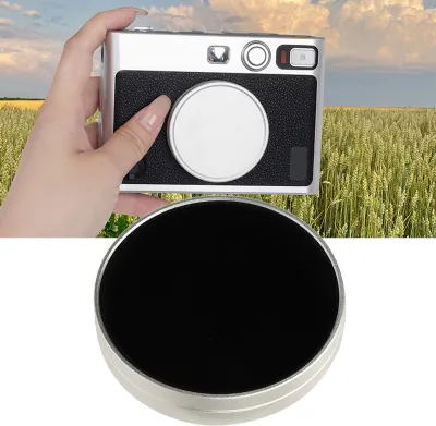 A hand holding a camera in front of a wheat field and sky.